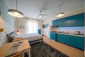 a room with a bed and a kitchen with blue cabinets at The Teal Studio in Kozani by Filos Inc in Kozani