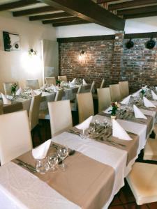 una fila de mesas en una habitación con manteles blancos en Hôtel Restaurant l’Éolienne, en Rouxmesnil-Bouteilles