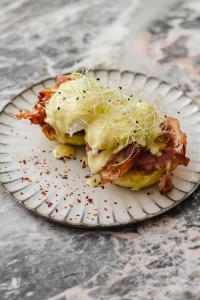 a paper plate with a sandwich with bacon and cheese at Kai 36 - Hotel zwischen Fels und Fluss in Graz