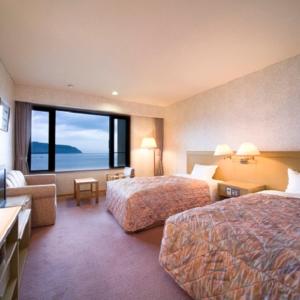 a hotel room with two beds and a large window at Kyukamura Ohmi-Hachiman in Omihachiman