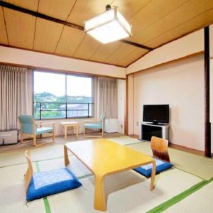 uma sala de estar com uma mesa e cadeiras e uma televisão em Kyukamura Ohmi-Hachiman em Omihachiman