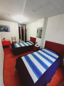 een slaapkamer met 2 bedden met blauwe en witte strepen bij Hotel Central in Latacunga