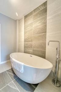 uma banheira branca numa casa de banho com azulejos em Guest Homes - Barton Road House em Hereford