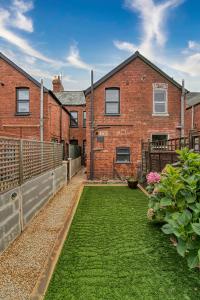 a backyard of a brick house with a grass yard at Guest Homes - Barton Road House in Hereford