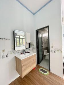 W białej łazience znajduje się umywalka i lustro. w obiekcie Leo's Homestay Phan Rang w mieście Phan Rang-Tháp Chàm