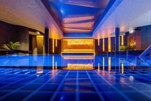 a swimming pool with blue lighting in a building at VICTORIA Hotel Klaipėda in Klaipėda