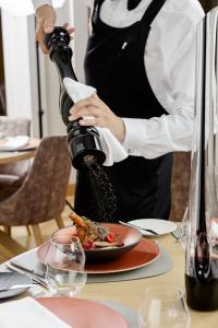 a woman pouring wine into a plate of food at VICTORIA Hotel Klaipėda in Klaipėda