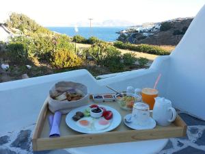 ein Tablett mit Frühstücksspeisen auf einem Tisch mit Meerblick in der Unterkunft Villa Margarita in Mykonos Stadt