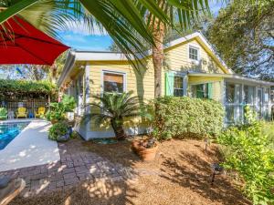 een geel huis met een zwembad en een rode parasol bij Island Bliss in Tybee Island