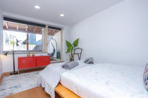 a bedroom with a bed with a red dresser and a window at My Botanical Garden & University Home in Coimbra