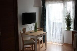 a room with a table and a tv and a window at Pension Sonneneck in Zwiesel