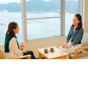 two women sitting in chairs in a room with a window at Kyukamura Minami-Awaji in Minamiawaji