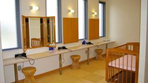 ein Badezimmer mit zwei Waschbecken, zwei Hockern und Spiegeln in der Unterkunft Kyukamura Minami-Awaji in Minamiawaji