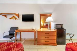 Habitación con escritorio, TV y silla. en Econo Lodge North, en North Fort Myers