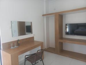 a room with a tv and a chair and a mirror at Maranda Deluxe Double Seaview room - B&B with pool. in Ukunda
