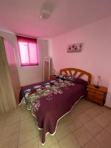 1 dormitorio con cama con colcha púrpura y ventana en Alpen1 Peñiscola Residencial, en Peñíscola