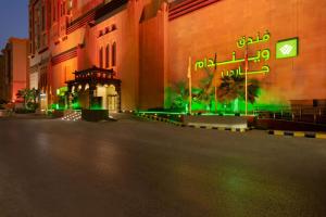 uma rua vazia em frente a um edifício com luzes verdes em Wyndham Garden Dammam em Dammam