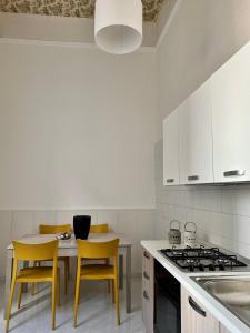 a kitchen with white cabinets and a table with yellow chairs at B&B Casa Caracciolo in Naples