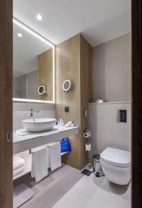 a bathroom with a sink and a toilet and a mirror at Radisson Blu Hotel, Kyiv City Centre in Kyiv