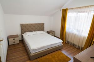 a bedroom with a bed with white sheets and yellow curtains at Pensiunea Matei in Petroşani