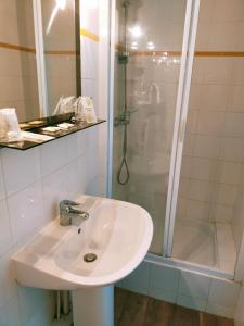 a bathroom with a sink and a shower at Hôtel Restaurant l’Éolienne in Rouxmesnil-Bouteilles