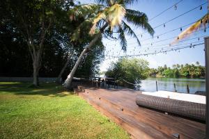 a wooden deck with a bench on the side of a lake at River Arc in Panadura