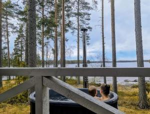 a woman and a child sitting in a hot tub at Niemi-Kapee Mansikka - Cozy cottage by the lake in Terälahti