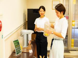 two women standing in a room holding a container at Kyukamura Takeno-Kaigan in Toyooka