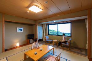 zwei Frauen sitzen in einem Wohnzimmer mit Fenster in der Unterkunft Kyukamura Takeno-Kaigan in Toyooka