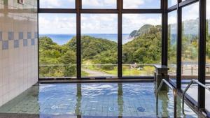 um quarto com uma piscina com vista para o oceano em Kyukamura Takeno-Kaigan em Toyooka