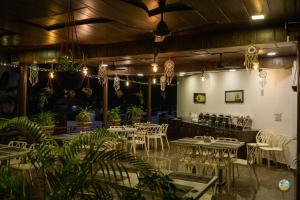 un restaurante con mesas blancas, sillas y plantas en La Gracia Resort, en Morjim