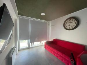 a red couch in a room with a clock on the wall at Departamento frente al mar en Monte Hermoso in Monte Hermoso