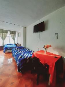 1 dormitorio con cama, mesa y TV en Hotel Central, en Latacunga