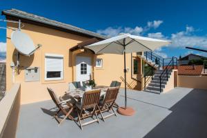 une terrasse avec une table, des chaises et un parasol dans l'établissement Apartment Sokol, à Batalaži