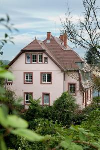 Casa blanca con ventanas rojas y arbustos en Wohnen im alten Pfarrhaus, en Herbolzheim