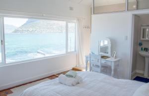 um quarto com uma grande janela, uma cama e um lavatório em Baytree Beach House em Kalk Bay