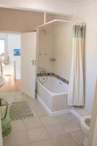 uma casa de banho branca com uma banheira e um WC em Baytree Beach House em Kalk Bay