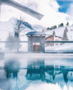 a pool of water in front of a building in the snow at Wellnesshotel Warther Hof in Warth am Arlberg