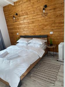 a bedroom with a large bed with a wooden wall at Cabana EvAy in Ocnele Mari