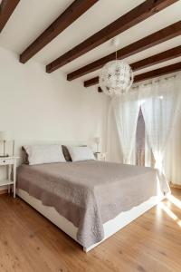 a white bedroom with a large bed and a chandelier at A central quiet place in Verbania in Verbania