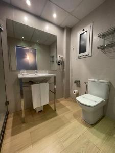 La salle de bains est pourvue de toilettes, d'un lavabo et d'un miroir. dans l'établissement SM Hotel Teatre Auditori, à Barcelone