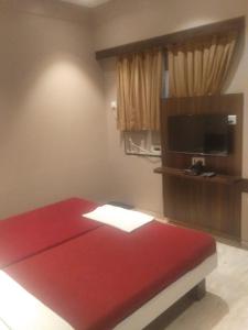 Habitación con cama roja y TV. en Ramakrishna International, en Nanded