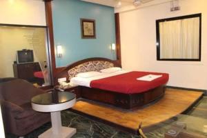 Schlafzimmer mit einem Bett, einem Tisch und einem Waschbecken in der Unterkunft Ramakrishna International in Nanded-Waghala
