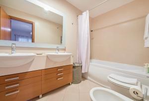 uma casa de banho com 2 lavatórios, uma banheira e um espelho. em Sunny apartament at Carcavelos Beach, by TimeCooler em Carcavelos