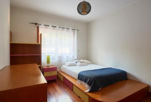 a bedroom with a bed and a desk and a window at Sunny apartament at Carcavelos Beach, by TimeCooler in Carcavelos