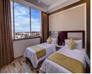 Regenta Inn Ranip Ahmedabad في أحمد آباد: غرفة فندقية بسريرين ونافذة كبيرة