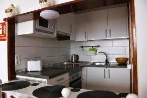 a kitchen with white cabinets and a sink and a microwave at Casa Regla in Puerto del Carmen
