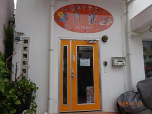 een oranje deur in een wit gebouw met een bord bij Minshuku Getto in Naha