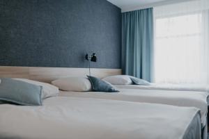 two white beds in a bedroom with a window at OREA Resort Devět Skal Vysočina in Sněžné