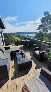 eine Terrasse mit Sofas und einem Tisch auf einer Terrasse in der Unterkunft Neu 55min von Oslo Ferienhaus mit Aussicht Sauna Wassersport in Berger